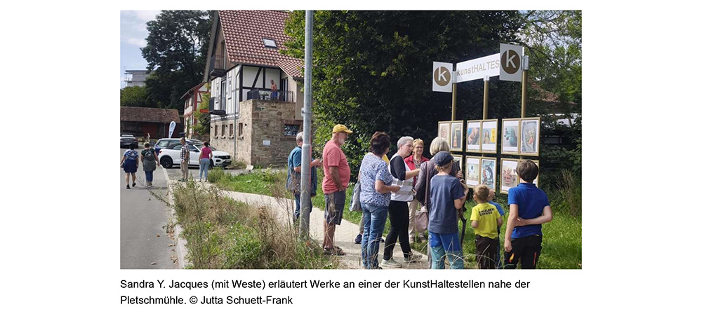 Sandra Y. Jacques (mit Weste) erläutert Werke an einer der KunstHaltestellen nahe der Pletschmühle. © Jutta Schuett-Frank
